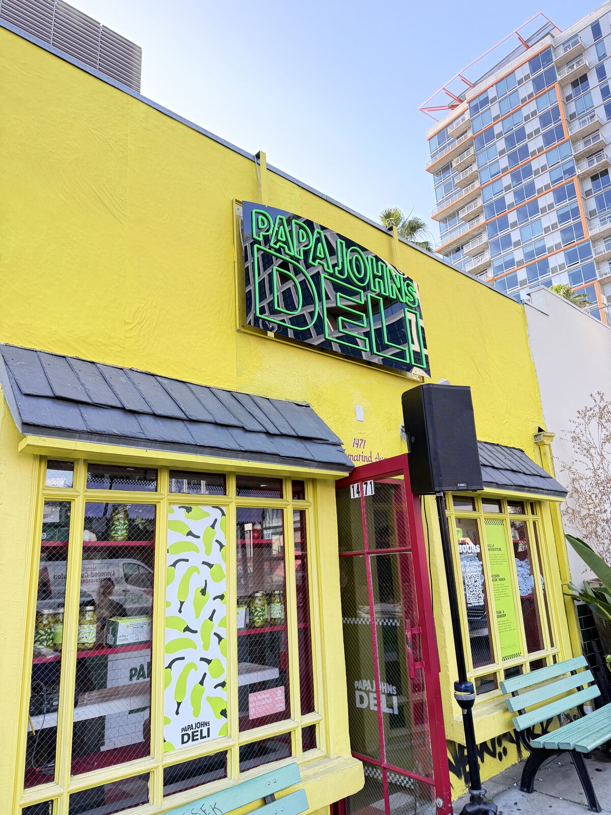 Exterior storefront or booth with vibrant yellow signage and decorated apparel displayed in windows