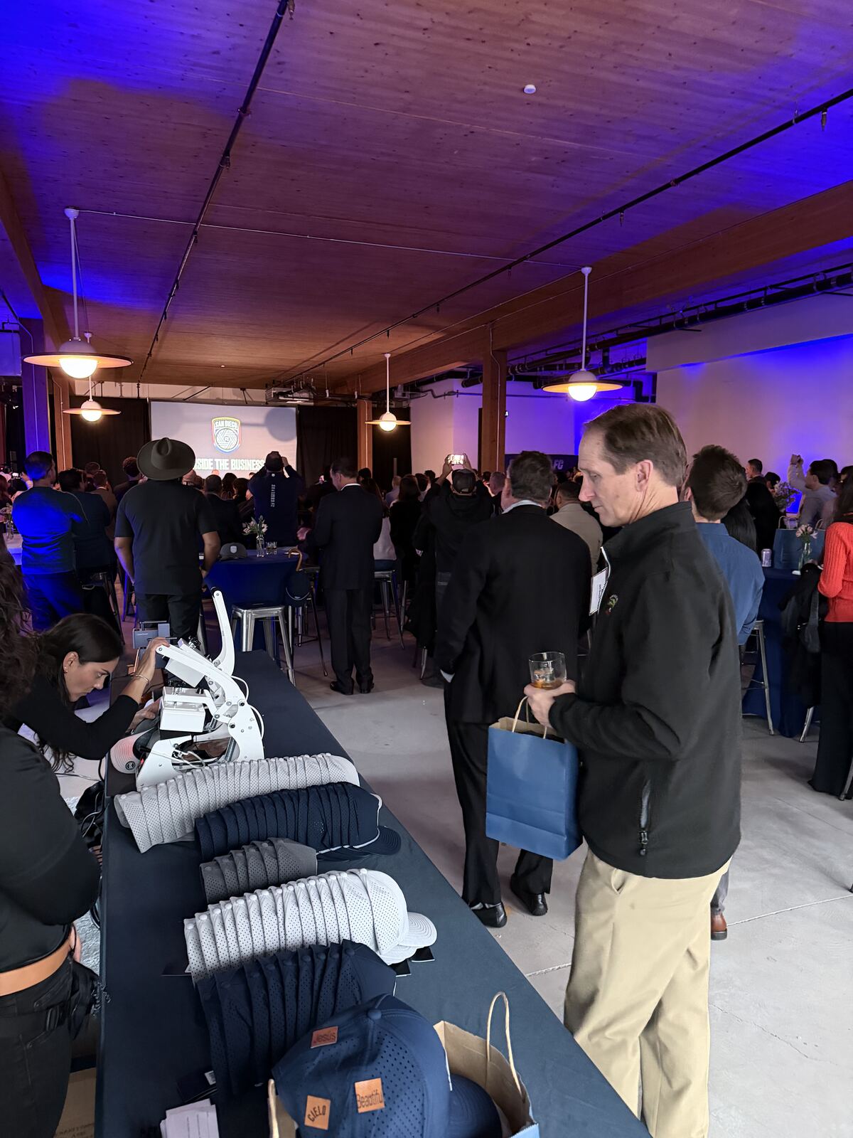 Live screen printing booth with multiple decorated shirts displayed and staff demonstrating the process to attendees
