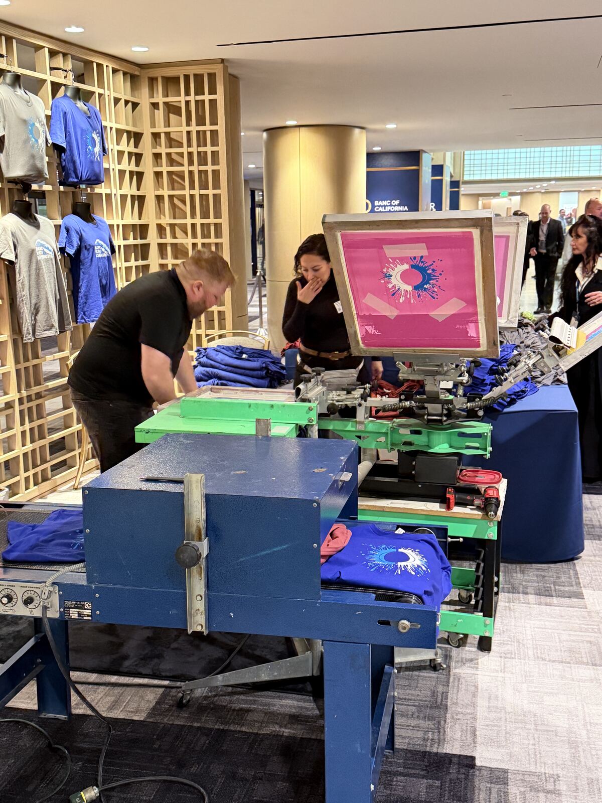 Screen-printed apparel displayed on tables at an event booth